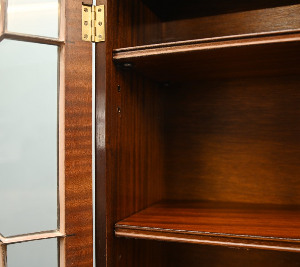 A Georgian Revival mahogany bookcase cabinet featuring a three-door astragal glazed upper section above three drawers and flame mahogany cupboard doors. View VII