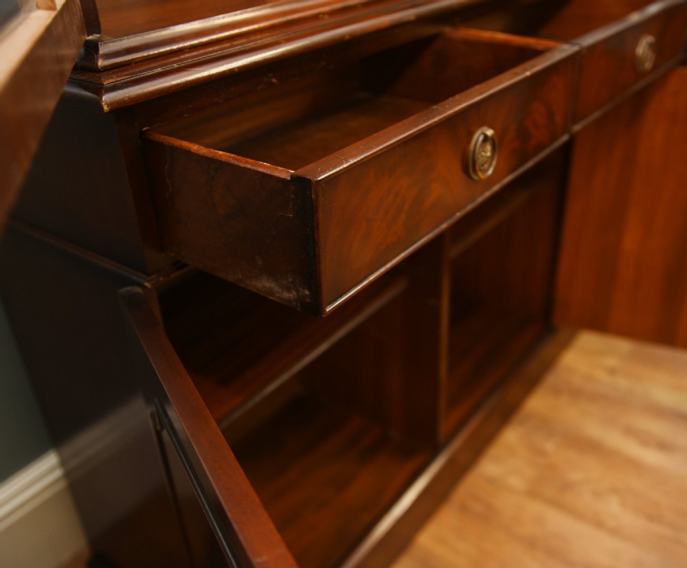 A Georgian Revival mahogany bookcase cabinet featuring a three-door astragal glazed upper section above three drawers and flame mahogany cupboard doors. View VIII