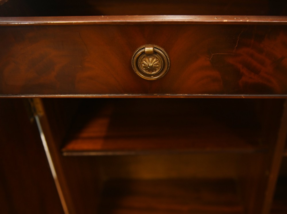 A Georgian Revival mahogany bookcase cabinet featuring a three-door astragal glazed upper section above three drawers and flame mahogany cupboard doors. View IX