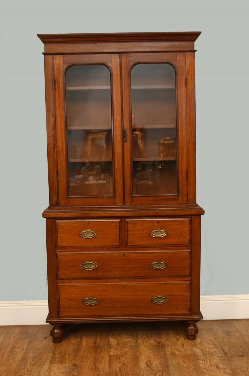 Victorian mahogany glazed bookcase featuring a two-door glass cabinet section resting on a chest of four drawers with brass handles. View II