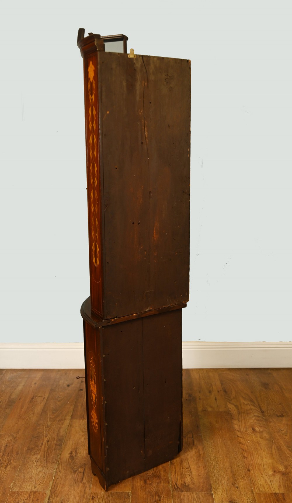 An Edwardian inlaid mahogany corner display cabinet featuring a swan-neck pediment, astragal glazed upper door, and marquetry urn designs on the lower panel. View IX