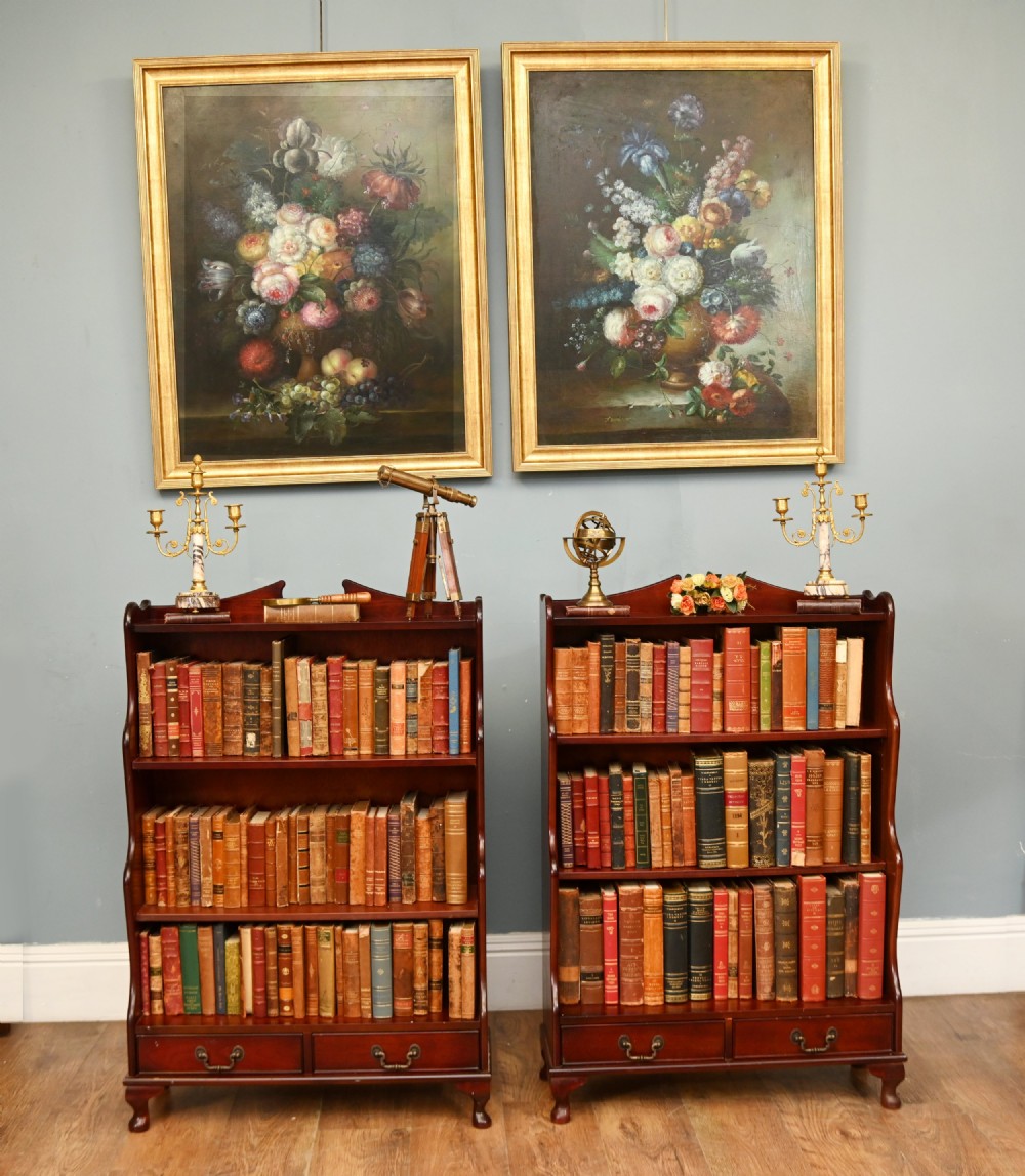 A pair of open mahogany waterfall bookcases featuring three graduated shelves, shaped side profiles, and two lower drawers. View II