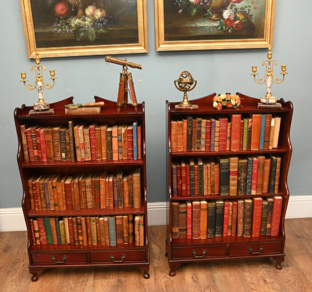 A pair of open mahogany waterfall bookcases featuring three graduated shelves, shaped side profiles, and two lower drawers. View III