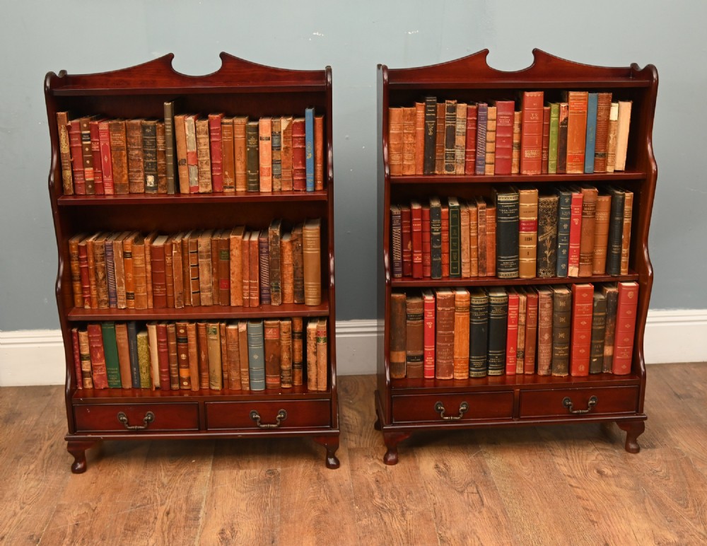 A pair of open mahogany waterfall bookcases featuring three graduated shelves, shaped side profiles, and two lower drawers. View IV