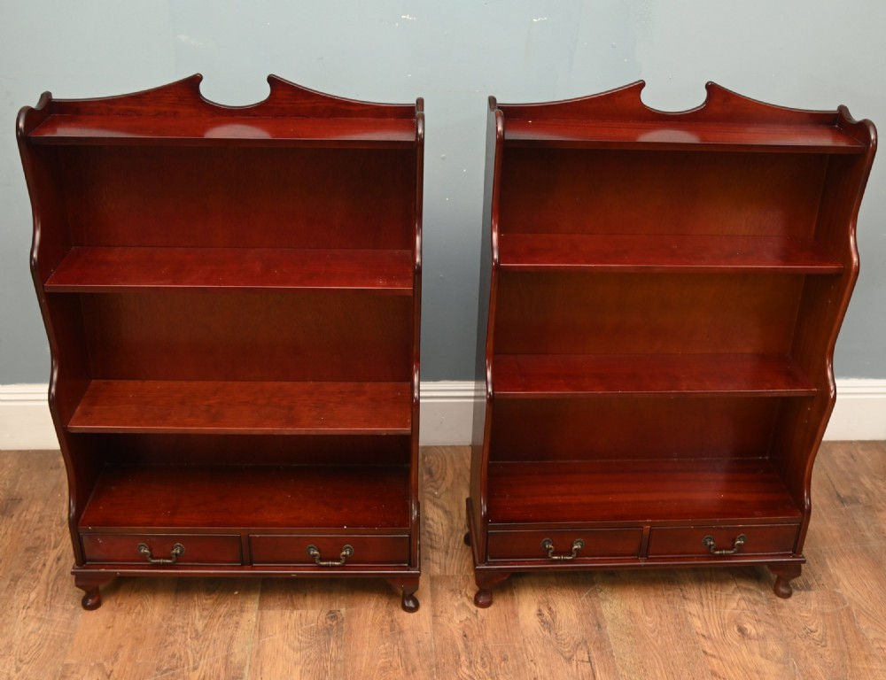 A pair of open mahogany waterfall bookcases featuring three graduated shelves, shaped side profiles, and two lower drawers. View V