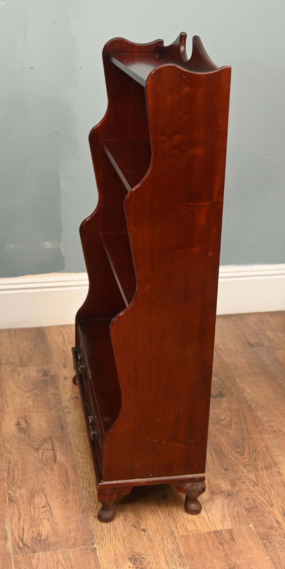 A pair of open mahogany waterfall bookcases featuring three graduated shelves, shaped side profiles, and two lower drawers. View VI