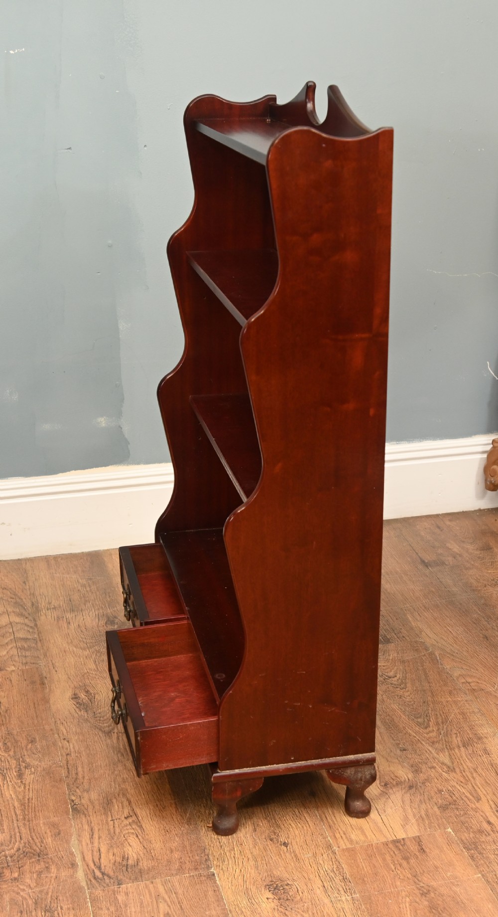 A pair of open mahogany waterfall bookcases featuring three graduated shelves, shaped side profiles, and two lower drawers. View VIII