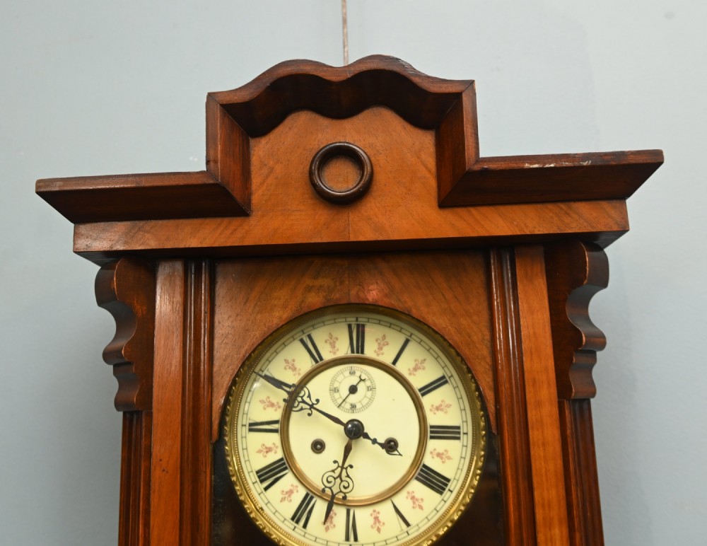 An antique walnut Vienna regulator wall clock featuring a glazed front door, brass pendulum, and turned bottom finials. View III