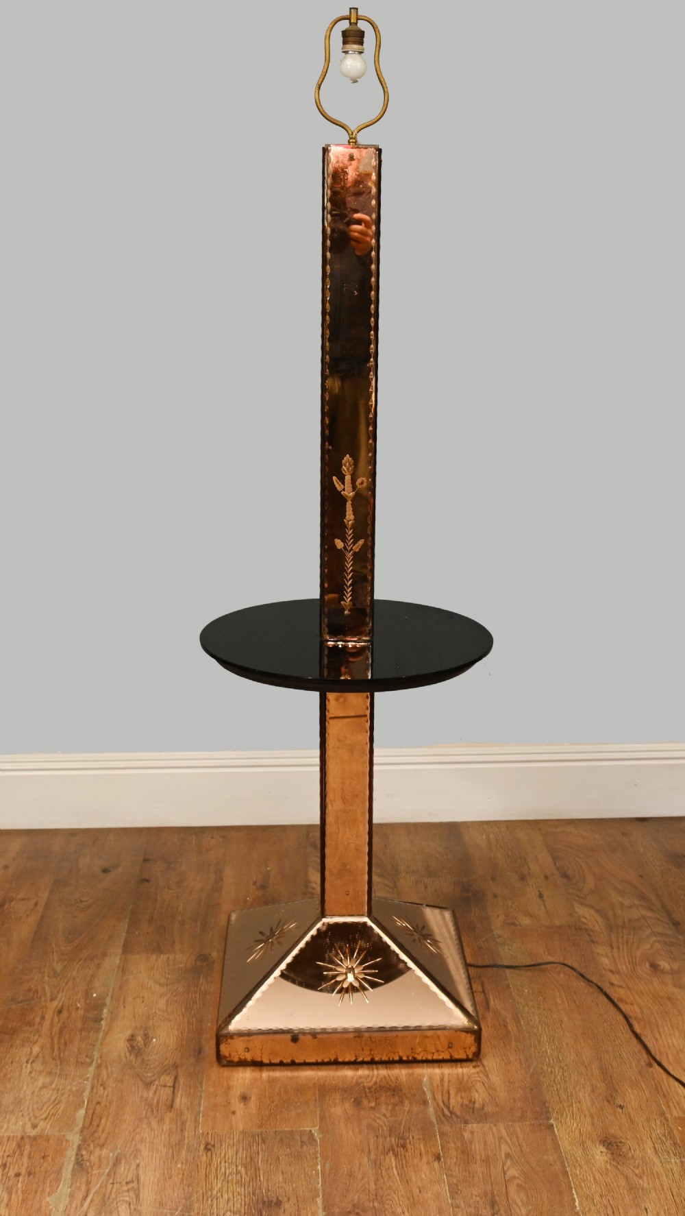 An Art Deco floor lamp featuring peach-tinted mirrored glass panels with etched starburst designs, a central black circular glass cocktail shelf, and a square pyramidal base. View II