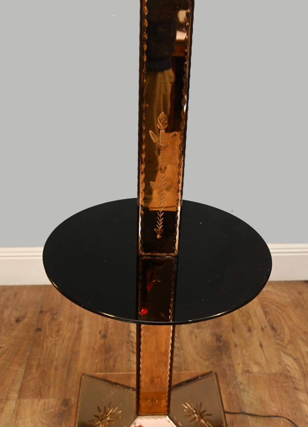 An Art Deco floor lamp featuring peach-tinted mirrored glass panels with etched starburst designs, a central black circular glass cocktail shelf, and a square pyramidal base. View IV