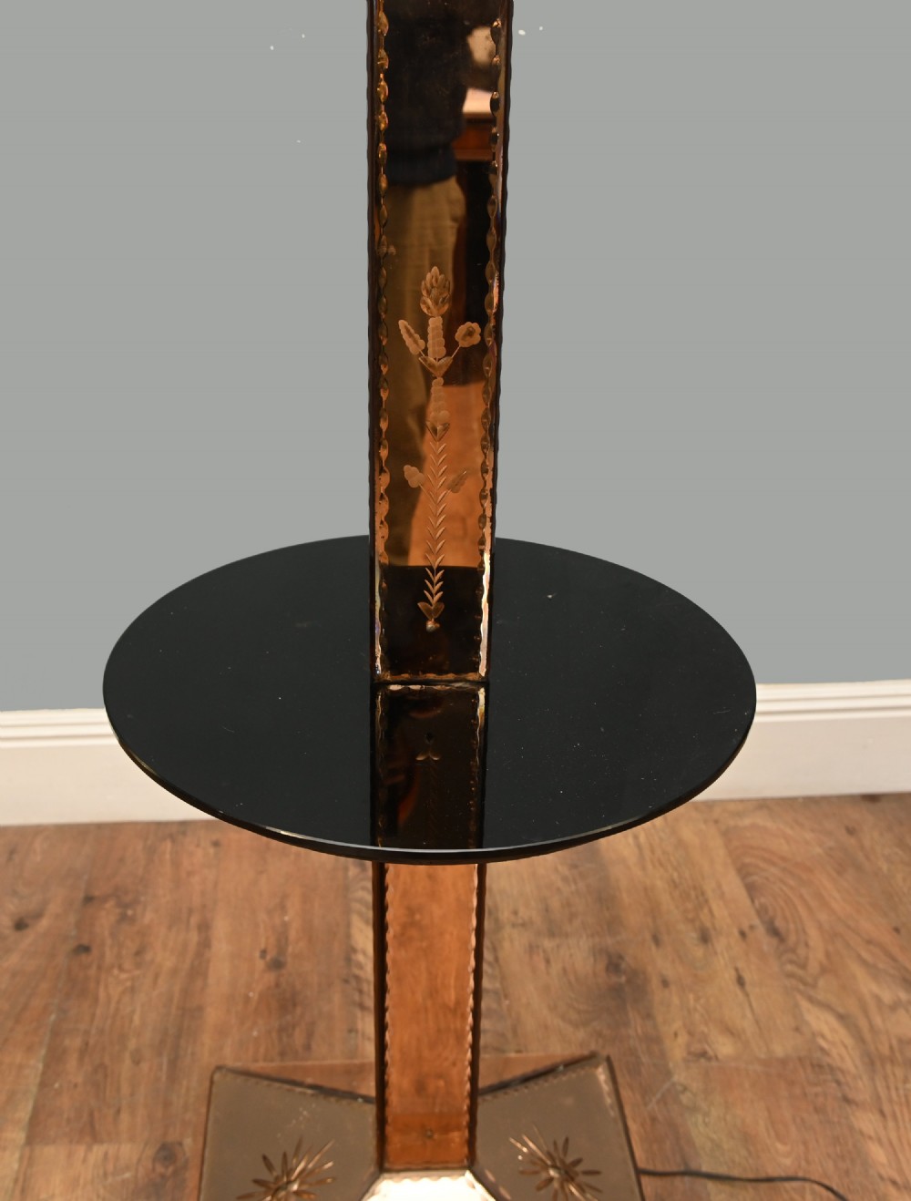 An Art Deco floor lamp featuring peach-tinted mirrored glass panels with etched starburst designs, a central black circular glass cocktail shelf, and a square pyramidal base. View V
