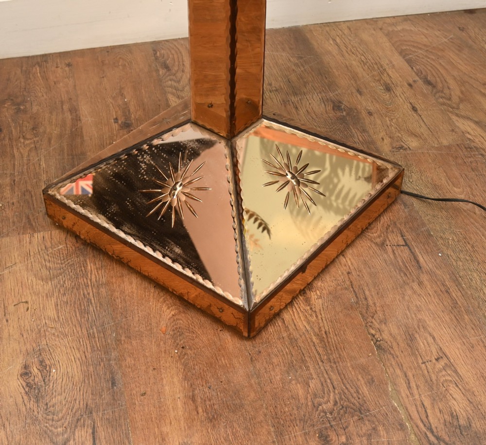 An Art Deco floor lamp featuring peach-tinted mirrored glass panels with etched starburst designs, a central black circular glass cocktail shelf, and a square pyramidal base. View VII