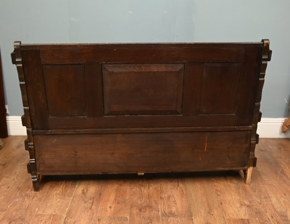 A dark Renaissance Revival carved oak hall settle featuring narrative relief panels on the backrest, carved lion head armrests, and a lifted storage seat. View IX