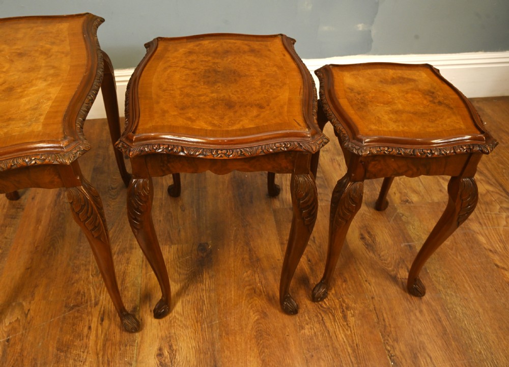 A set of three graduated burr walnut nest tables featuring carved serpentine edges, cabriole legs with carved knees, and claw-and-ball feet. View V