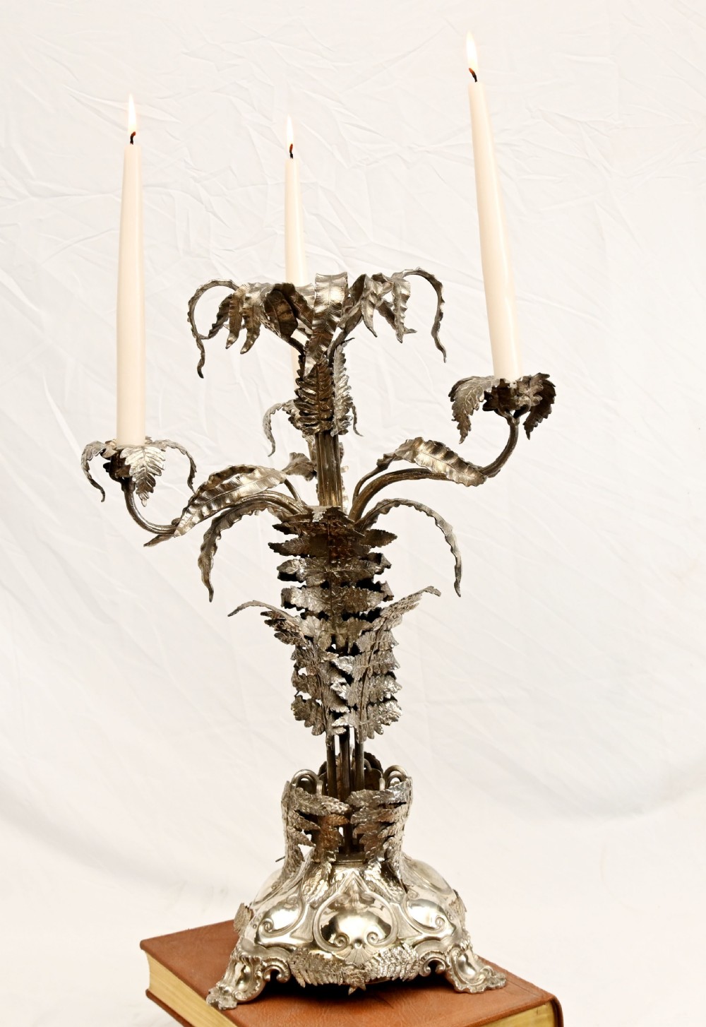 A silver-plated three-light candelabra designed in the shape of a palm tree with detailed foliate leaves and a scrolled base.