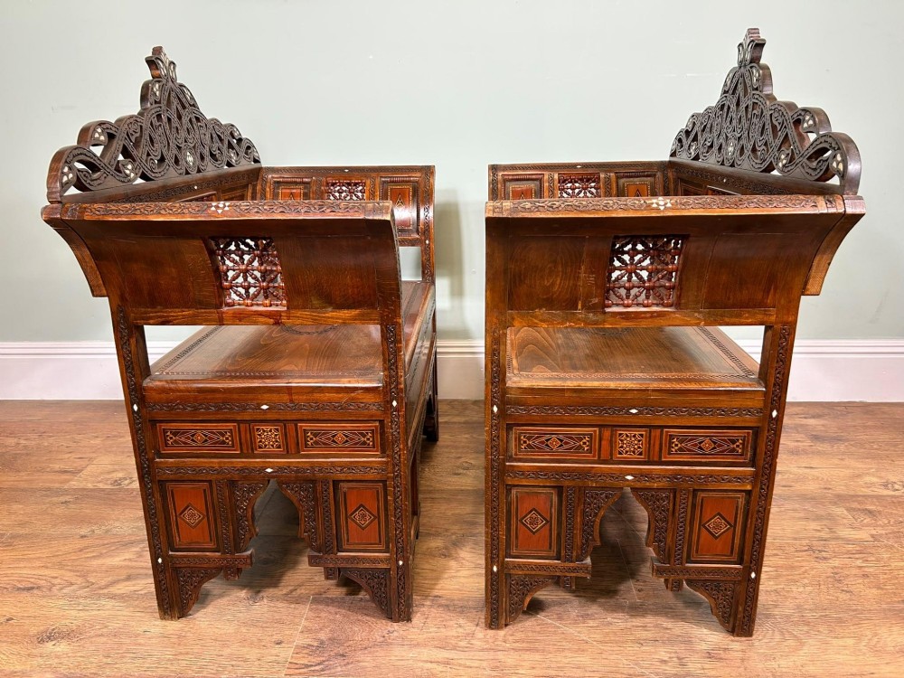A pair of warm brown wooden armchairs featuring elaborate carved openwork crestings and geometric mother-of-pearl inlays across the seats and panels. View II