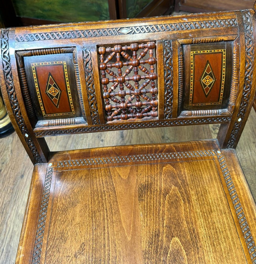 A pair of warm brown wooden armchairs featuring elaborate carved openwork crestings and geometric mother-of-pearl inlays across the seats and panels. View VIII