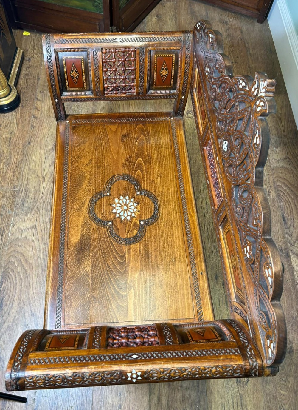 A pair of warm brown wooden armchairs featuring elaborate carved openwork crestings and geometric mother-of-pearl inlays across the seats and panels. View IX