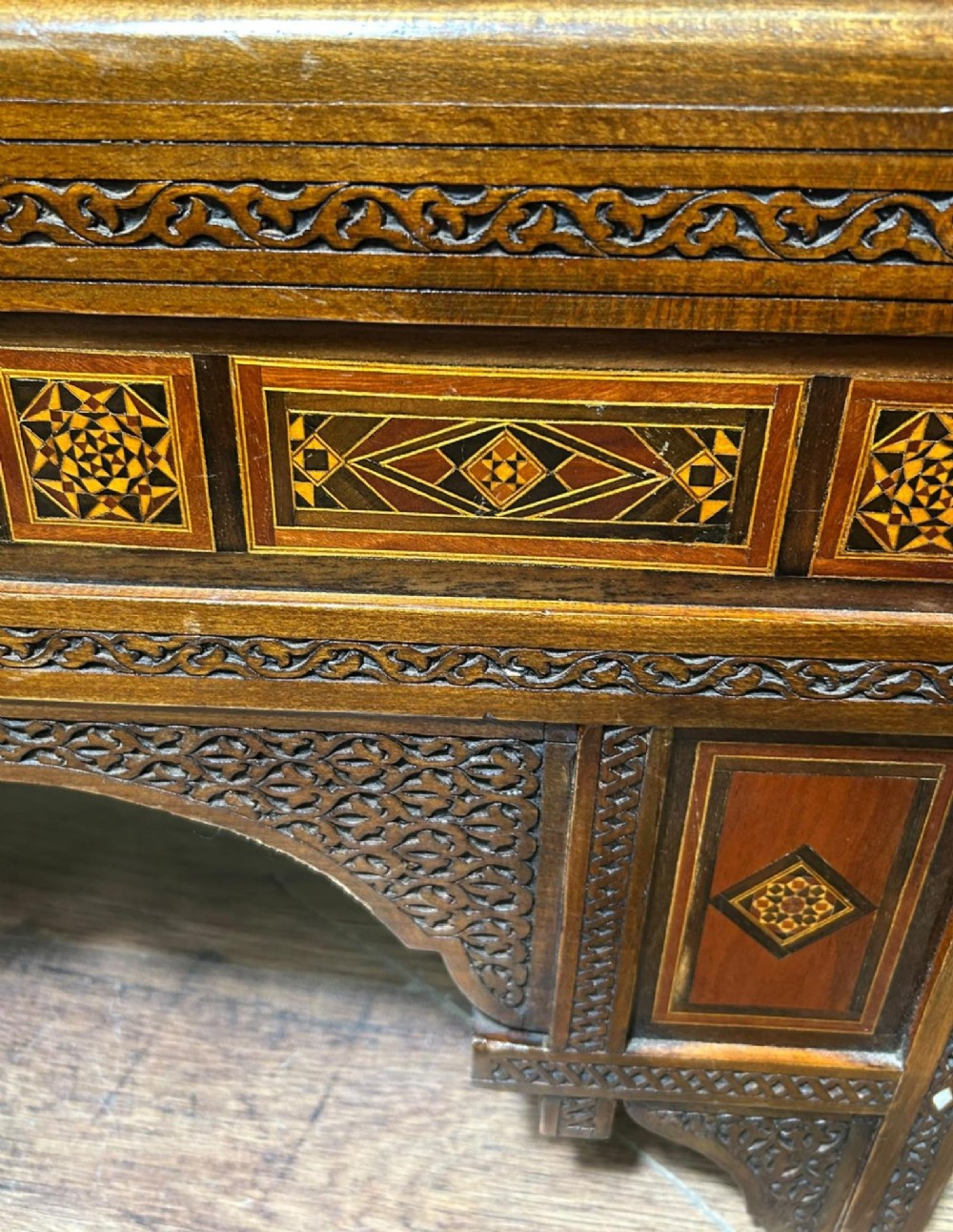 A pair of warm brown wooden armchairs featuring elaborate carved openwork crestings and geometric mother-of-pearl inlays across the seats and panels. View X