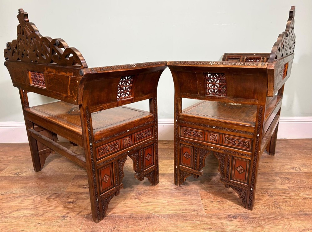 A pair of warm brown wooden armchairs featuring elaborate carved openwork crestings and geometric mother-of-pearl inlays across the seats and panels. View XIV