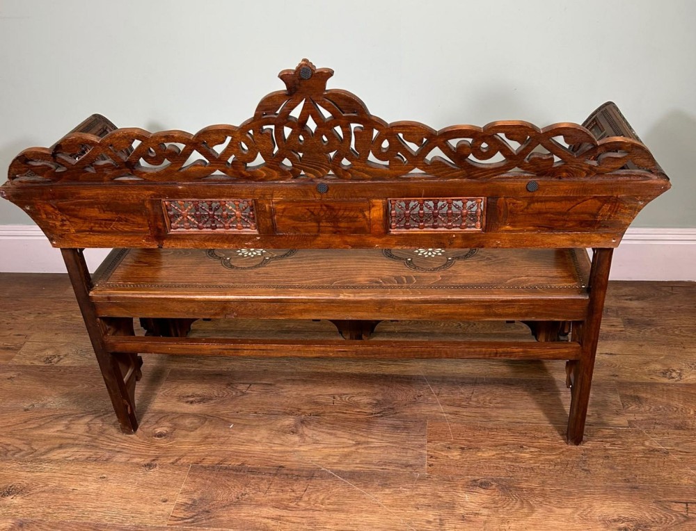 A 19th-century Syrian wooden bench featuring geometric marquetry inlay, mother-of-pearl accents, an openwork carved crest, and arched apron support. View III