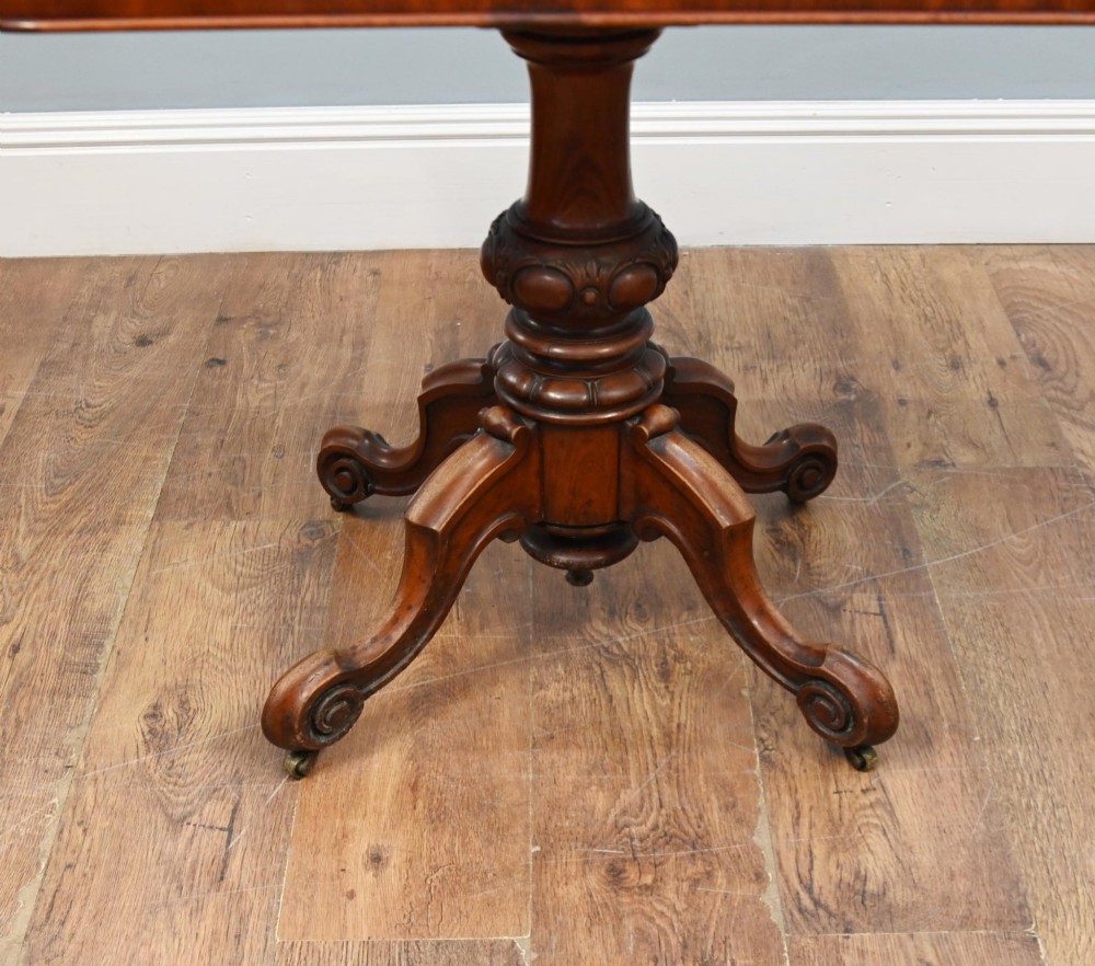 A Victorian mahogany fold-over card table with a rectangular top supported by a central carved pedestal and four scroll-cut legs on castors. View III