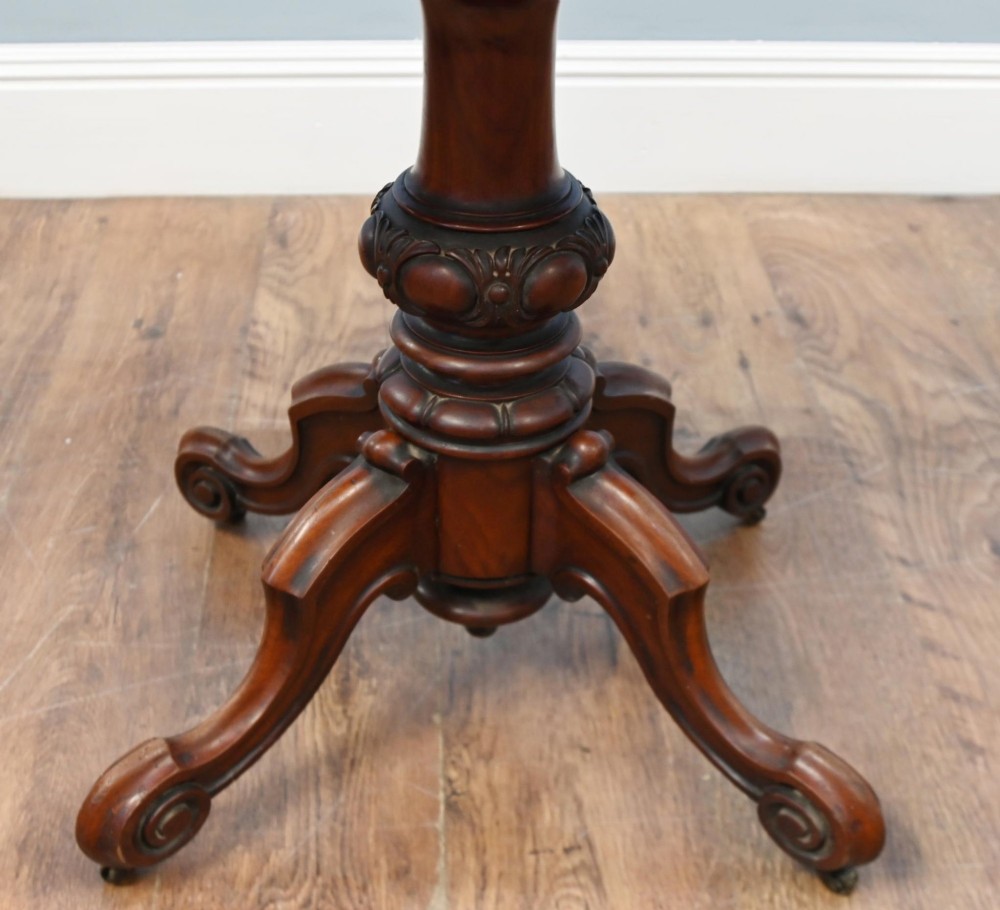 A Victorian mahogany fold-over card table with a rectangular top supported by a central carved pedestal and four scroll-cut legs on castors. View VIII