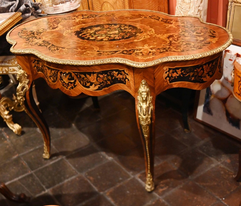 A French Louis XV style centre table featuring intricate floral marquetry, a serpentine top, cabriole legs, and gilded bronze mounts.