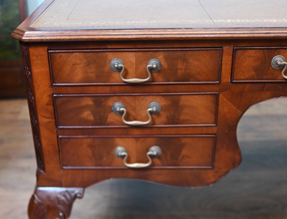 Late Victorian mahogany writing desk featuring a tan gilt-tooled leather inset top, brass swan-neck handles, and carved cabriole legs with ball-and-claw feet. View V