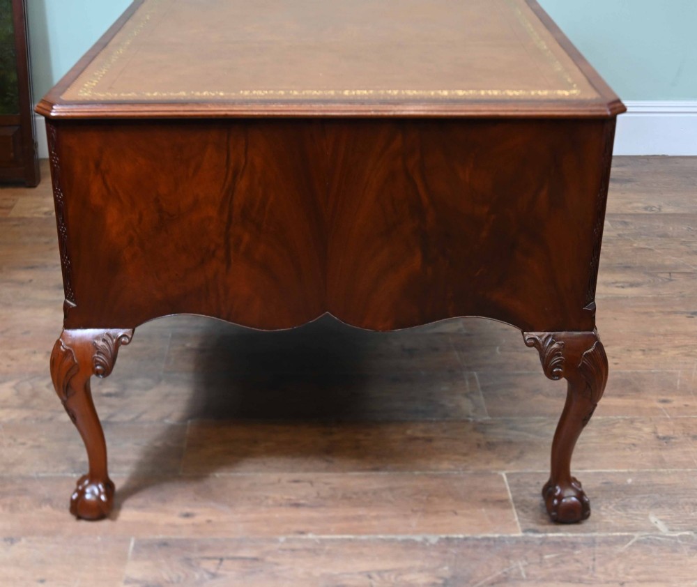 Late Victorian mahogany writing desk featuring a tan gilt-tooled leather inset top, brass swan-neck handles, and carved cabriole legs with ball-and-claw feet. View X