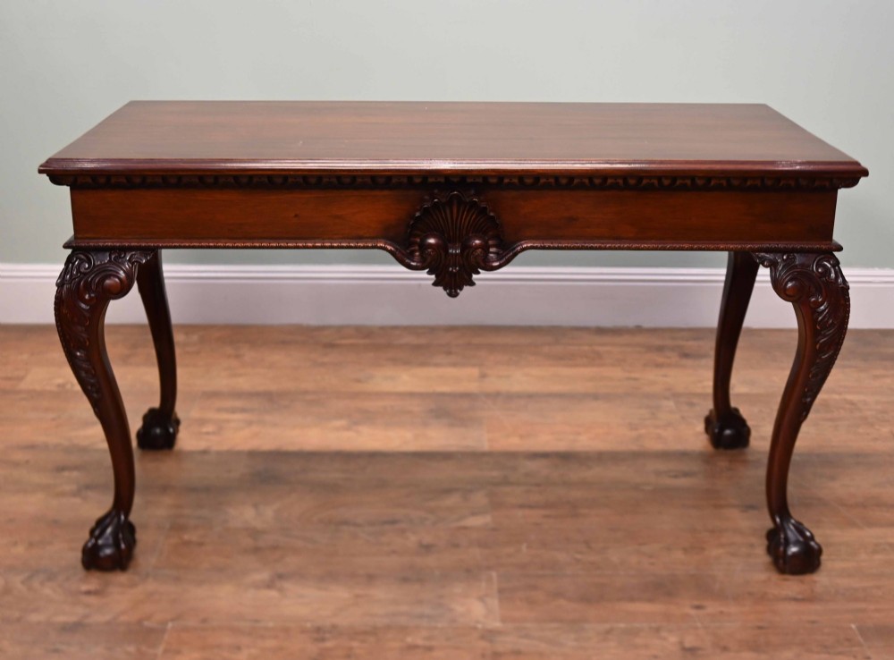 A rectangular Chippendale revival mahogany console table featuring a central carved apron shell detail, cabriole legs, and carved claw and ball feet.