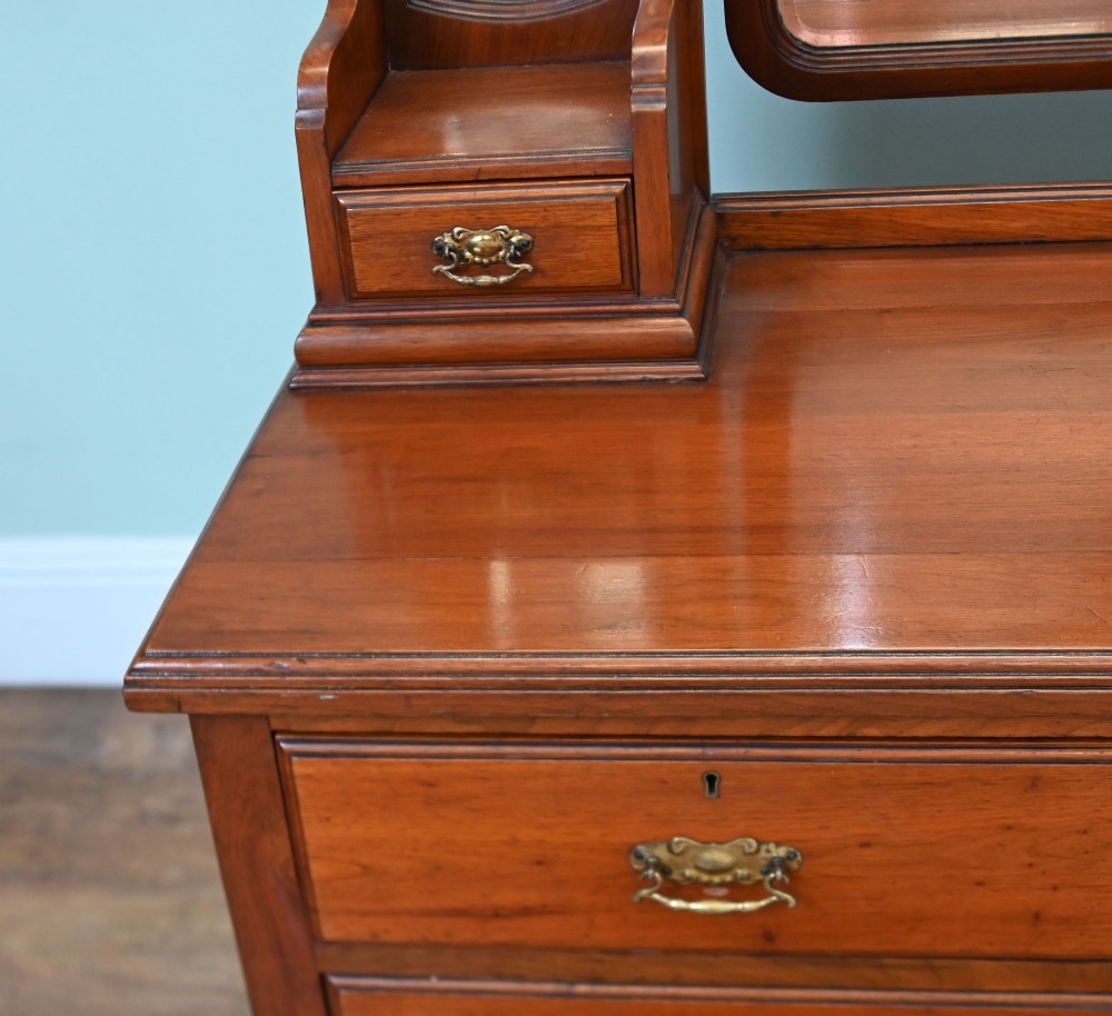 An Edwardian mahogany dressing table featuring a central swinging mirror flanked by two trinket drawers, set above a chest with three drawers and brass drop handles. View V