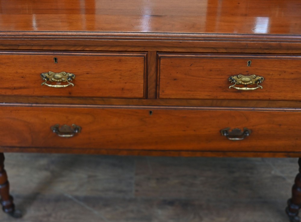 An Edwardian mahogany dressing table featuring a central swinging mirror flanked by two trinket drawers, set above a chest with three drawers and brass drop handles. View VI
