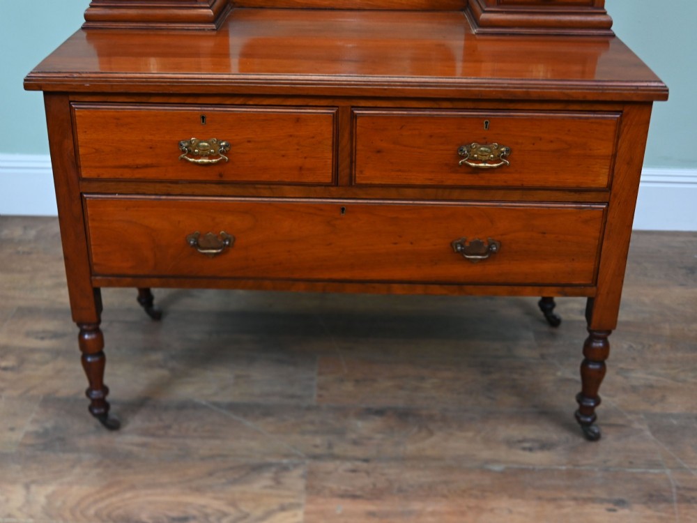 An Edwardian mahogany dressing table featuring a central swinging mirror flanked by two trinket drawers, set above a chest with three drawers and brass drop handles. View VII