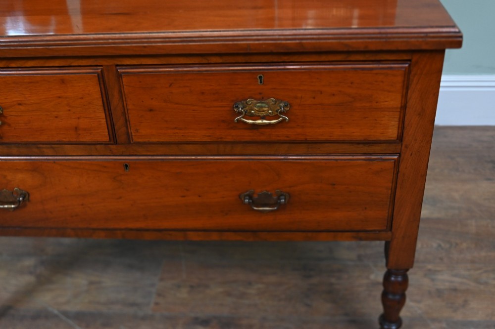 An Edwardian mahogany dressing table featuring a central swinging mirror flanked by two trinket drawers, set above a chest with three drawers and brass drop handles. View VIII
