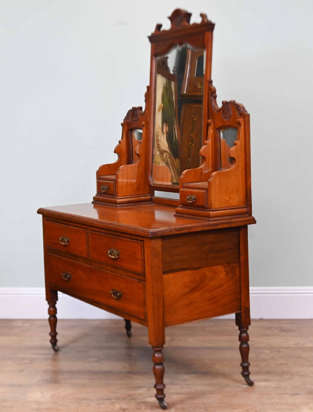 An Edwardian mahogany dressing table featuring a central swinging mirror flanked by two trinket drawers, set above a chest with three drawers and brass drop handles. View IX