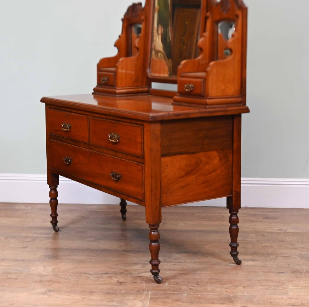 An Edwardian mahogany dressing table featuring a central swinging mirror flanked by two trinket drawers, set above a chest with three drawers and brass drop handles. View X