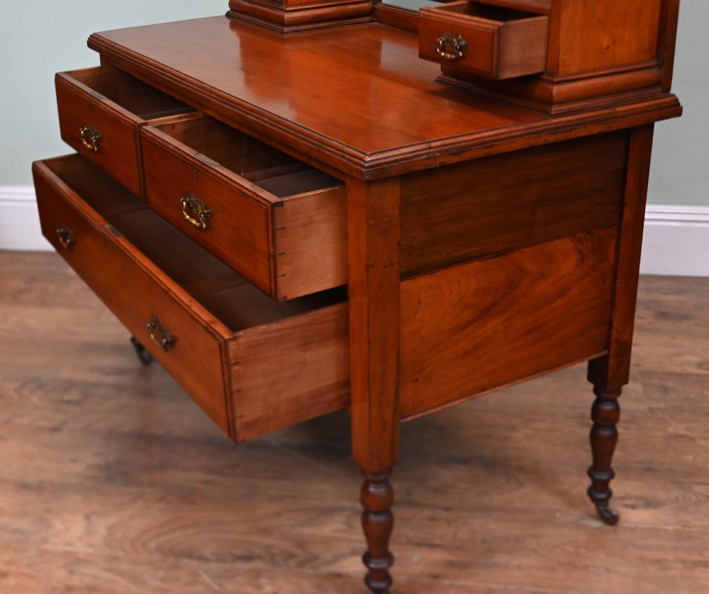 An Edwardian mahogany dressing table featuring a central swinging mirror flanked by two trinket drawers, set above a chest with three drawers and brass drop handles. View XI