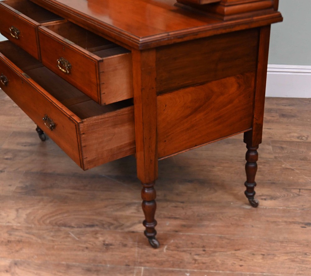An Edwardian mahogany dressing table featuring a central swinging mirror flanked by two trinket drawers, set above a chest with three drawers and brass drop handles. View XII