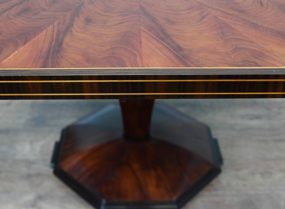 An octagonal Art Deco mahogany centre table featuring a sunburst veneer top, banded rim, and a tapered hexagonal pedestal base. View VII