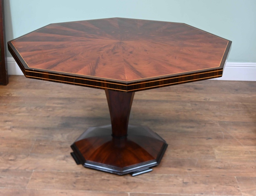 An octagonal Art Deco mahogany centre table featuring a sunburst veneer top, banded rim, and a tapered hexagonal pedestal base. View IX