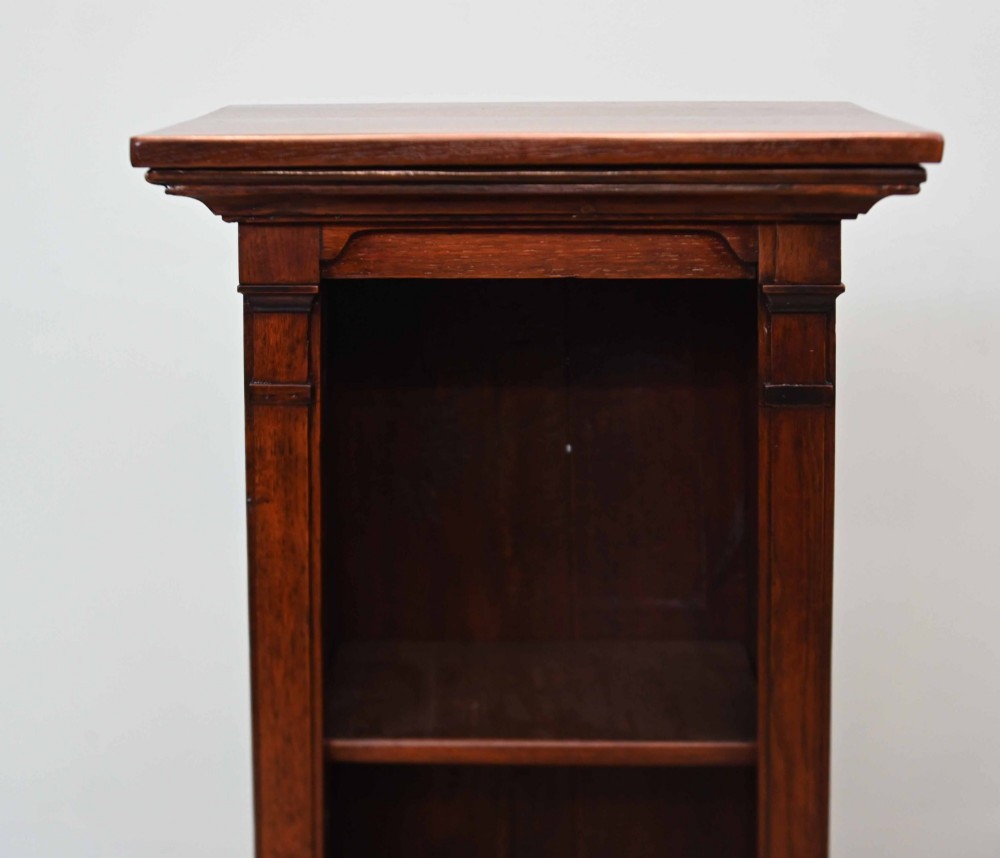 A tall, narrow late 19th-century dark oak open bookcase featuring fixed shelves, a moulded top cornice, and a sturdy plinth base. View V