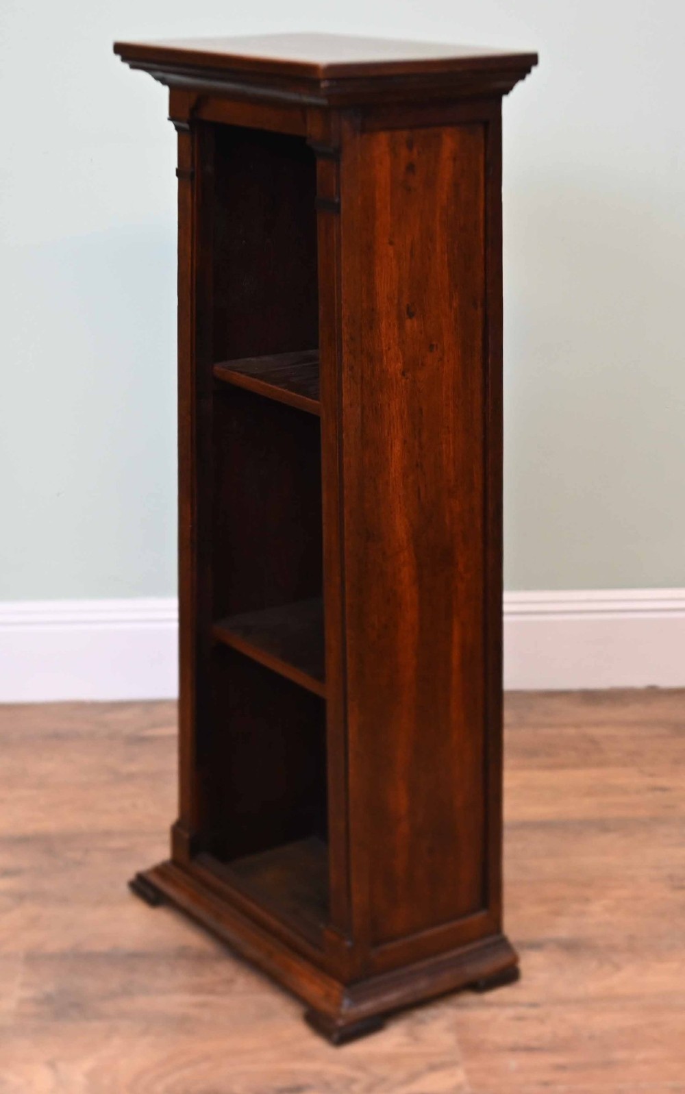 A tall, narrow late 19th-century dark oak open bookcase featuring fixed shelves, a moulded top cornice, and a sturdy plinth base. View VI