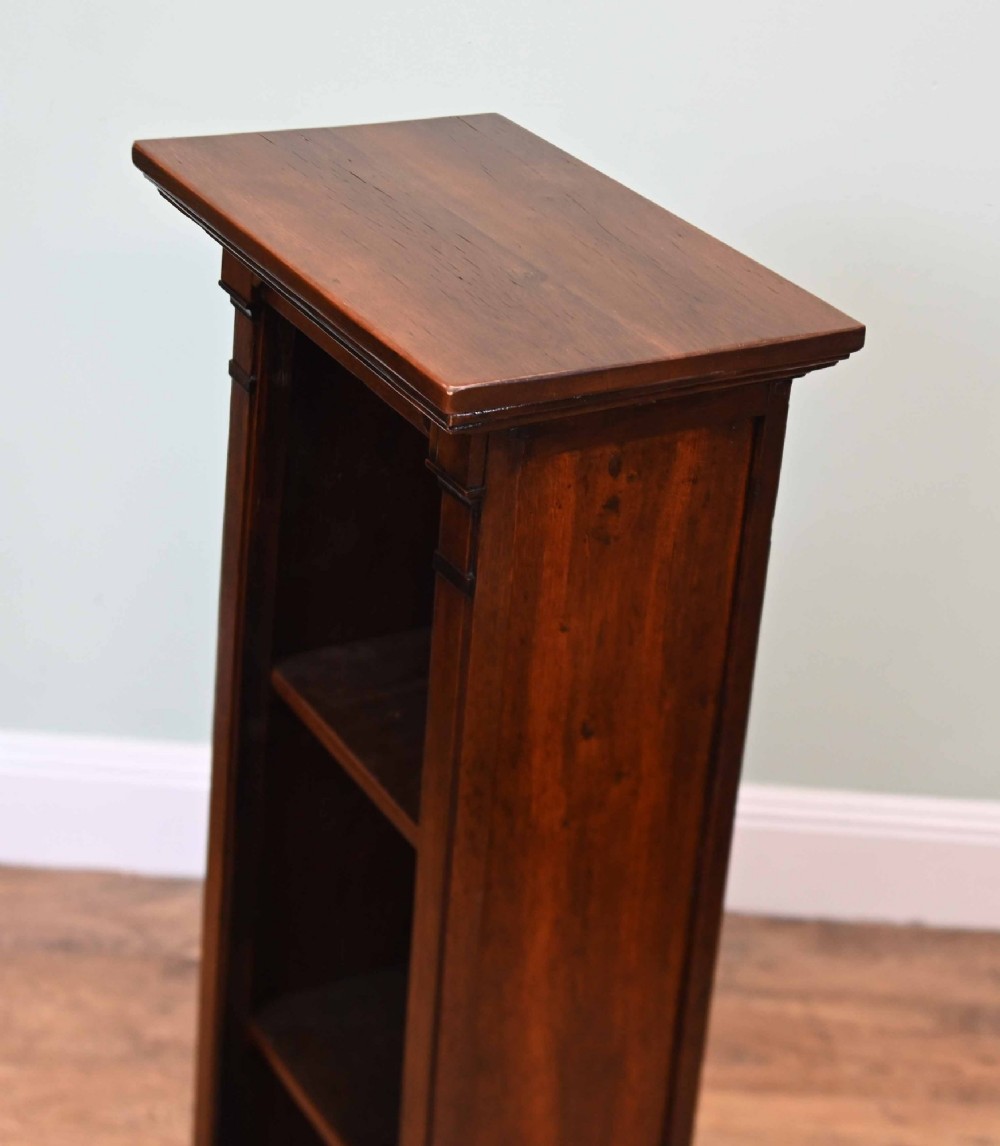 A tall, narrow late 19th-century dark oak open bookcase featuring fixed shelves, a moulded top cornice, and a sturdy plinth base. View VII