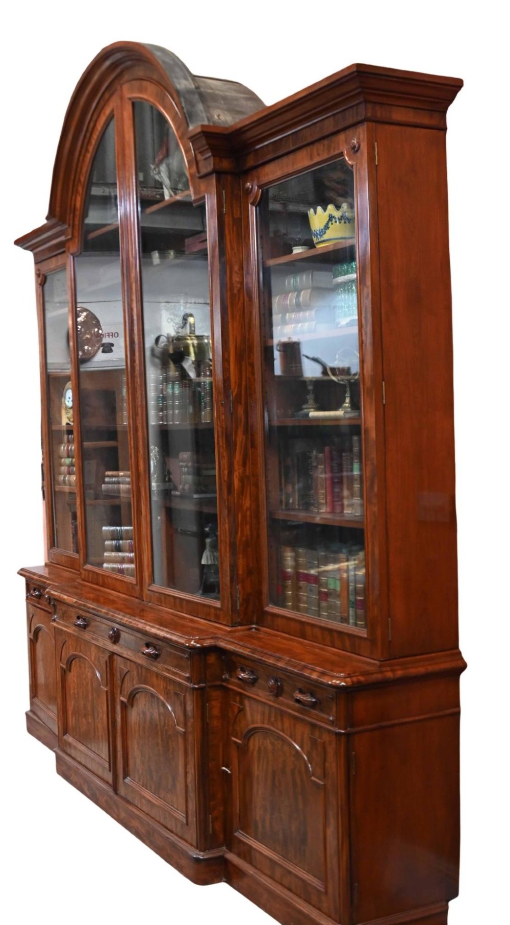 A large Victorian mahogany breakfront library bookcase featuring an arched central section with glazed upper doors over solid panelled cupboards. View V