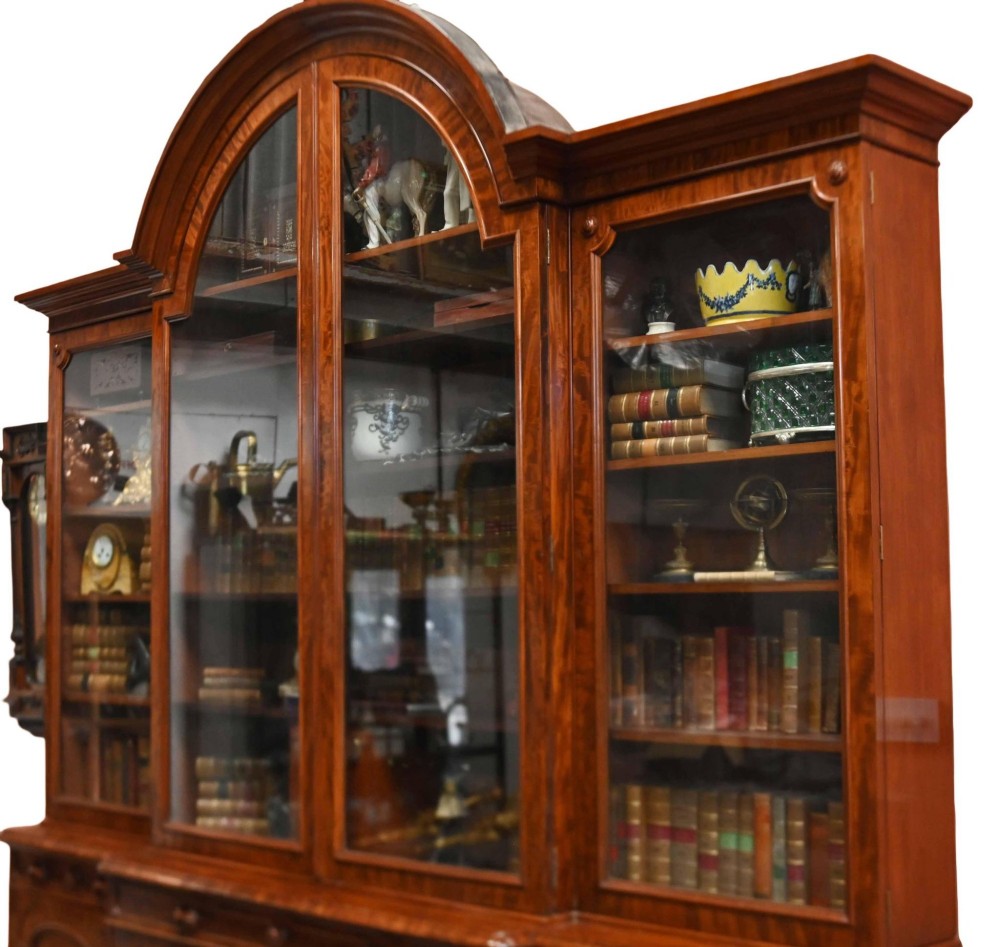 A large Victorian mahogany breakfront library bookcase featuring an arched central section with glazed upper doors over solid panelled cupboards. View VI