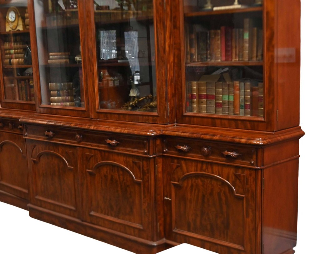 A large Victorian mahogany breakfront library bookcase featuring an arched central section with glazed upper doors over solid panelled cupboards. View VII