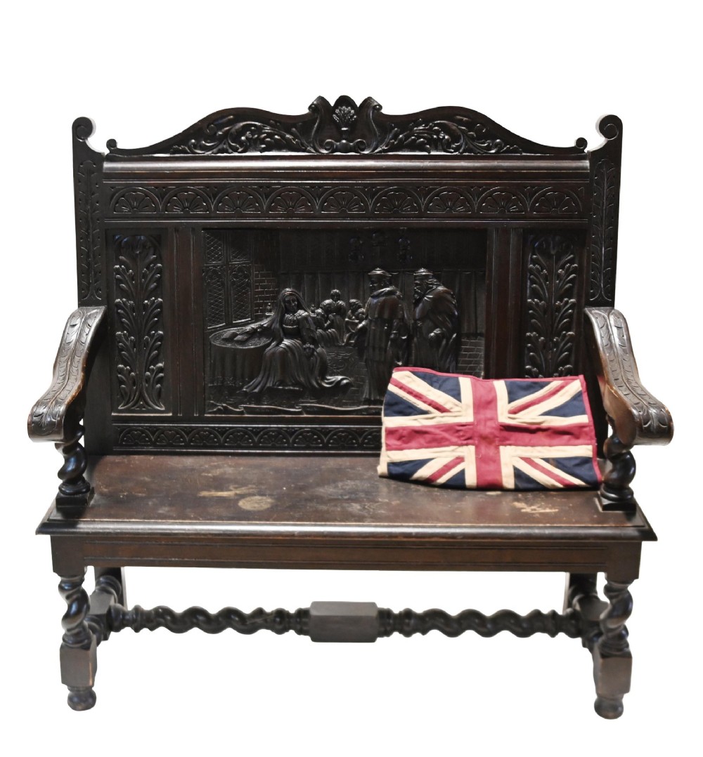 A late 19th-century dark carved walnut hall bench featuring a pictorial relief back panel, scrolled armrests, and turned stretchers. View II