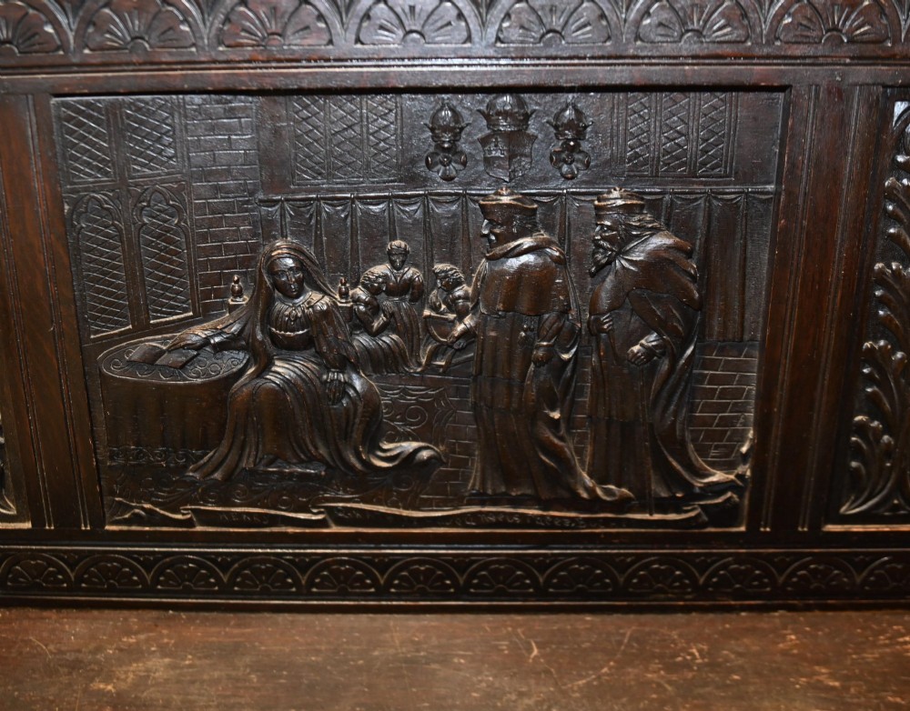 A late 19th-century dark carved walnut hall bench featuring a pictorial relief back panel, scrolled armrests, and turned stretchers. View IV