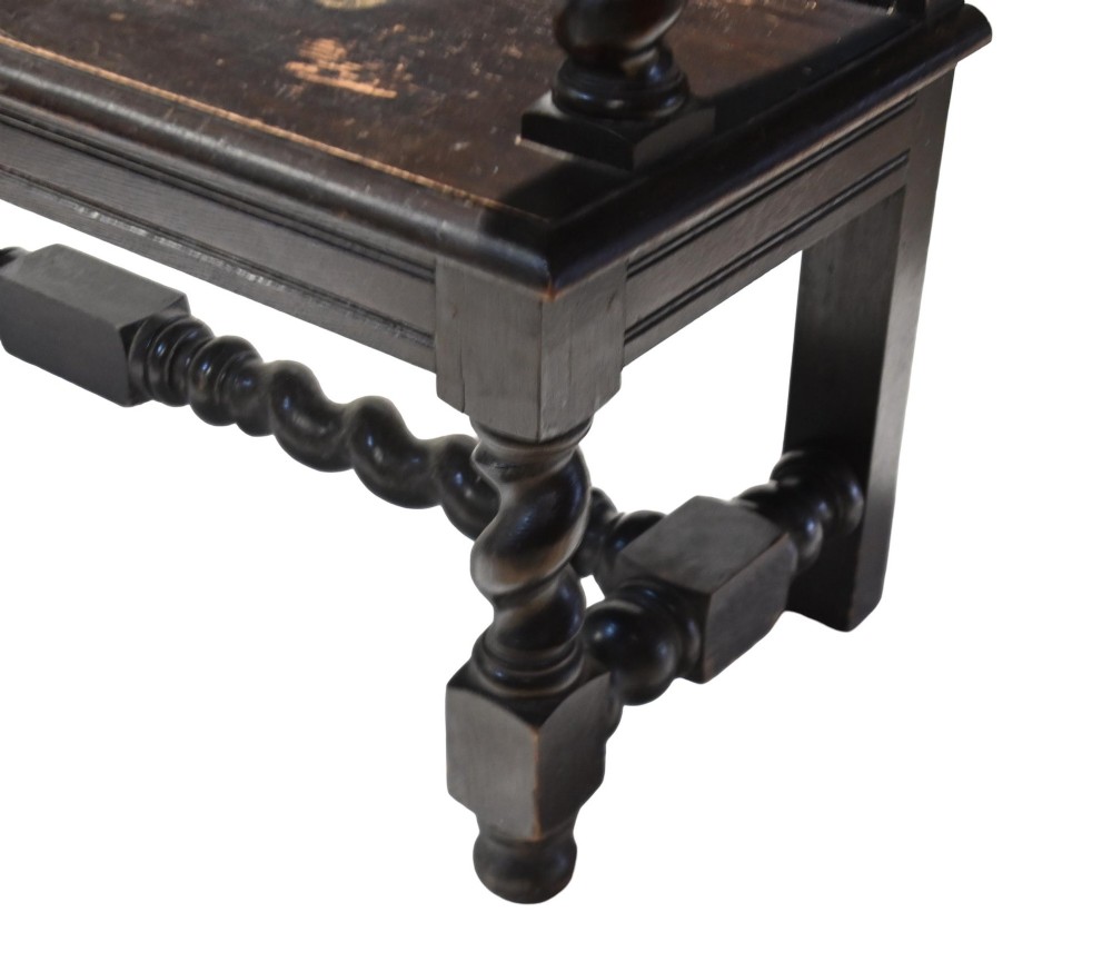 A late 19th-century dark carved walnut hall bench featuring a pictorial relief back panel, scrolled armrests, and turned stretchers. View IX
